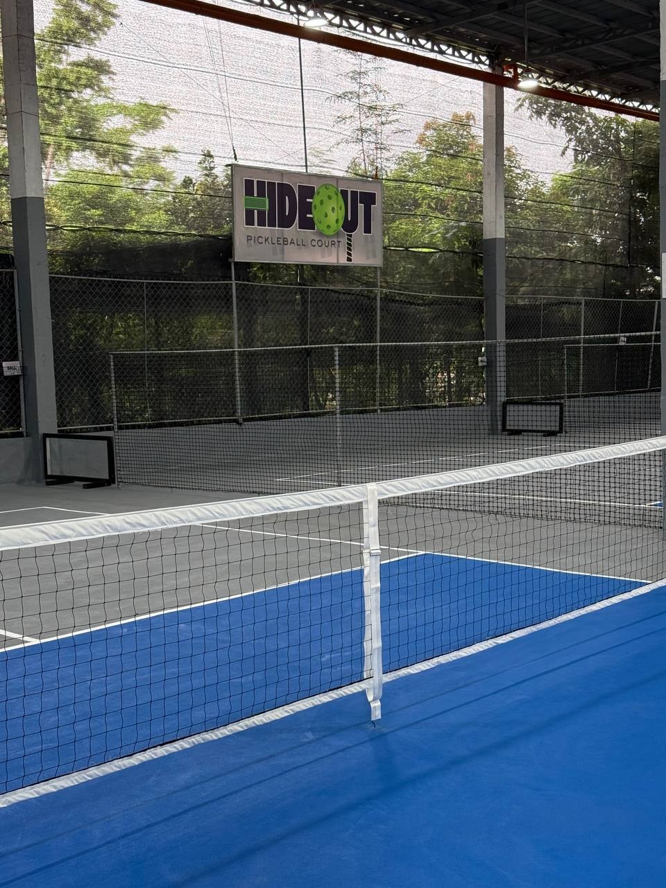 Net and kitchen on a HIDEOUT court, with the club sign beyond